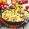 Omelet with vegetables and cheese. Frittata in a frying pan
